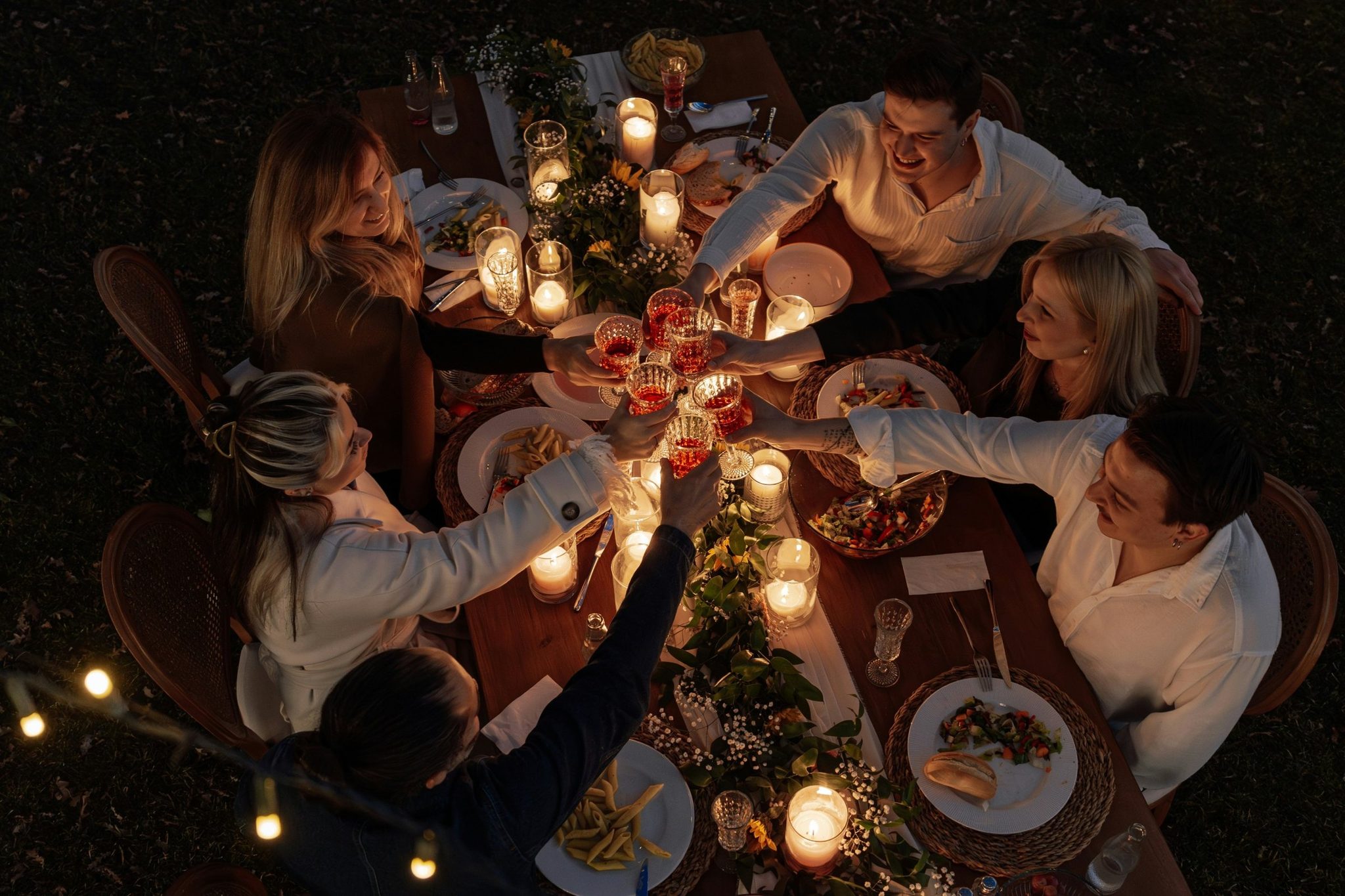 Friends raising glasses over a candlelit dinner